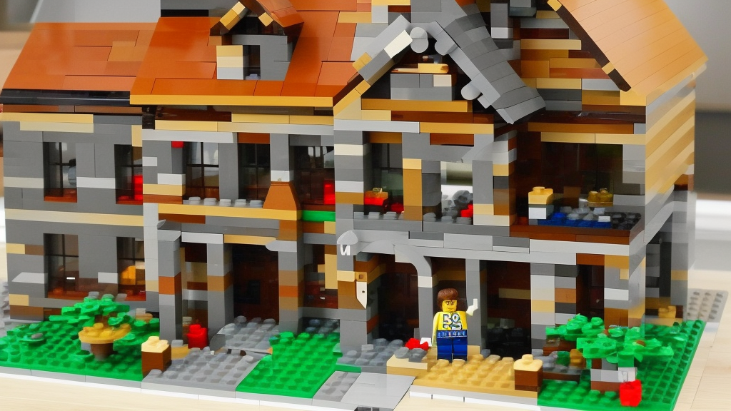 A man in a stone house building house from LEGO